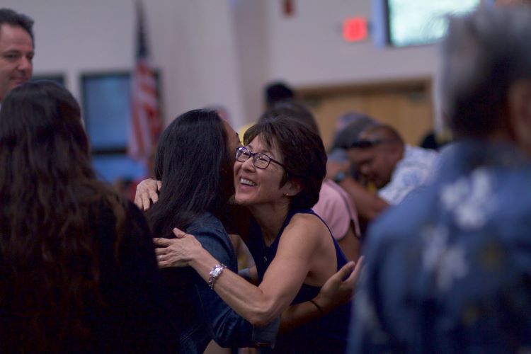 Two women hugging in a room of people