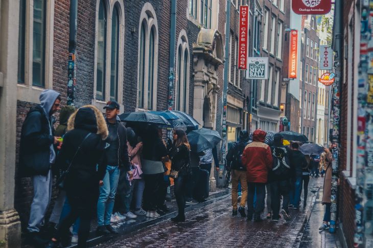 People lined up holding umbrellas on a wet city street
