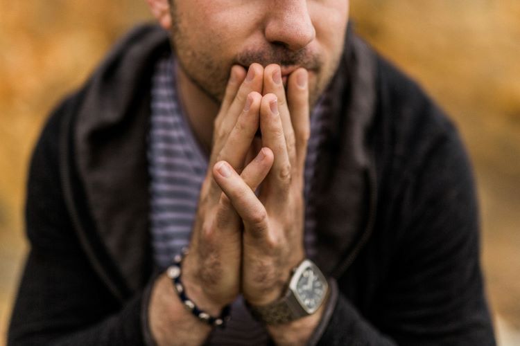 A man, hands clasped to his lips at an intervention for alcoholism