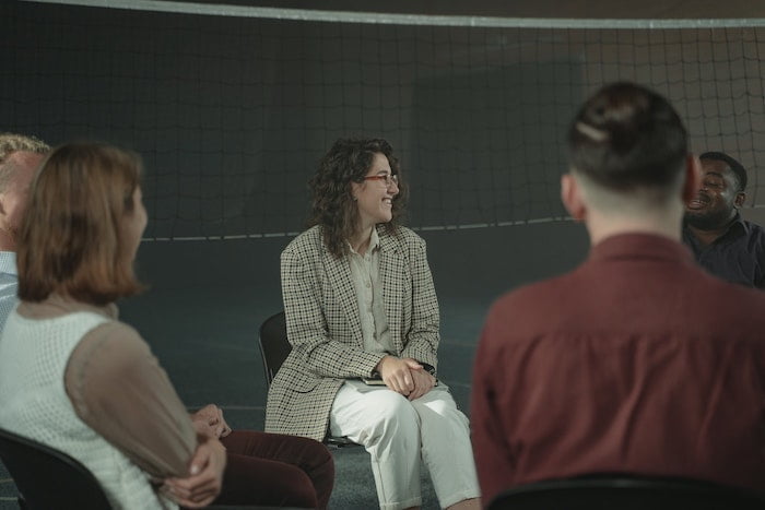 Attendees sat in a circle and smiling during a Narcotics Anonymous meeting