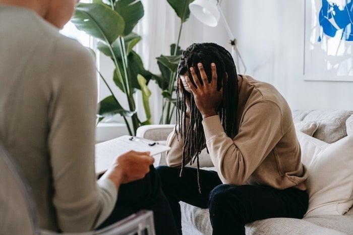 Man holding his head and talking to a Nar-Anon sponsor