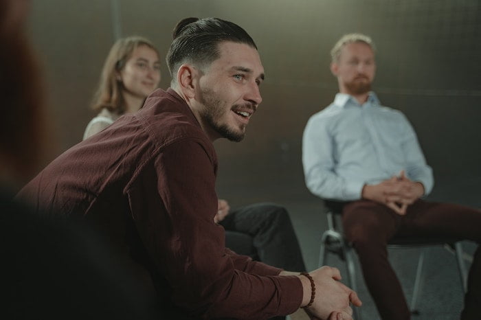 Man smiling and talking whilst at a Narcotics Anonymous group meeting