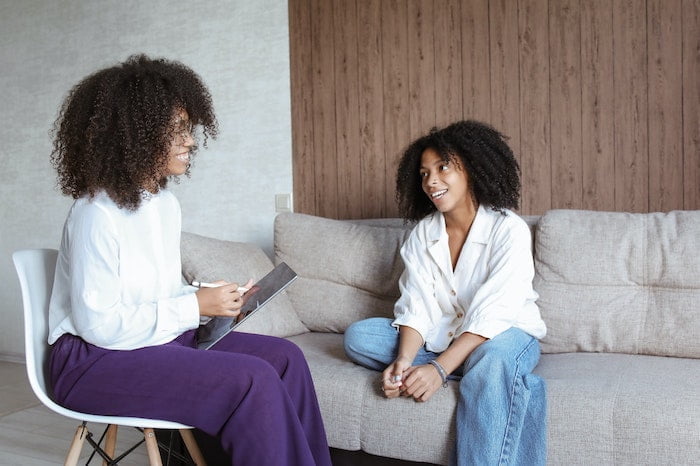Patient on a sofa speaking to a smiling therapist during Acceptance and Commitment Therapy