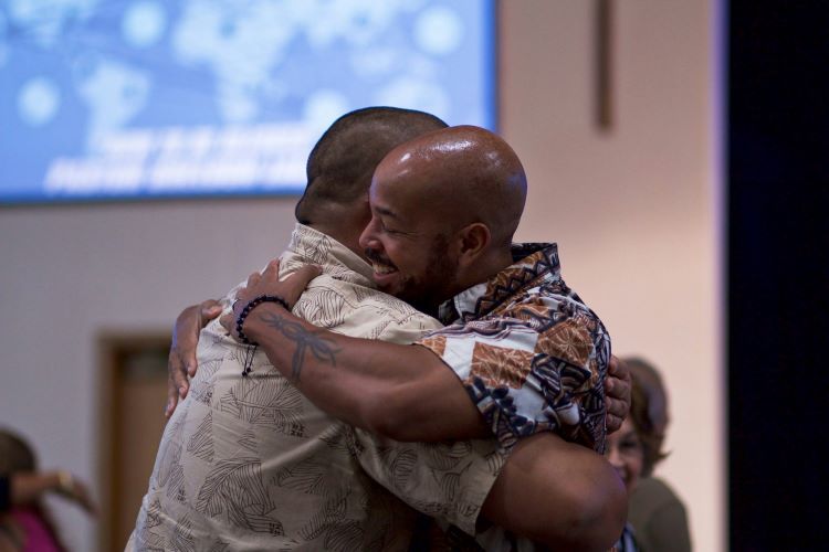 Two men hugging at an Alcoholics Anonymous meeting