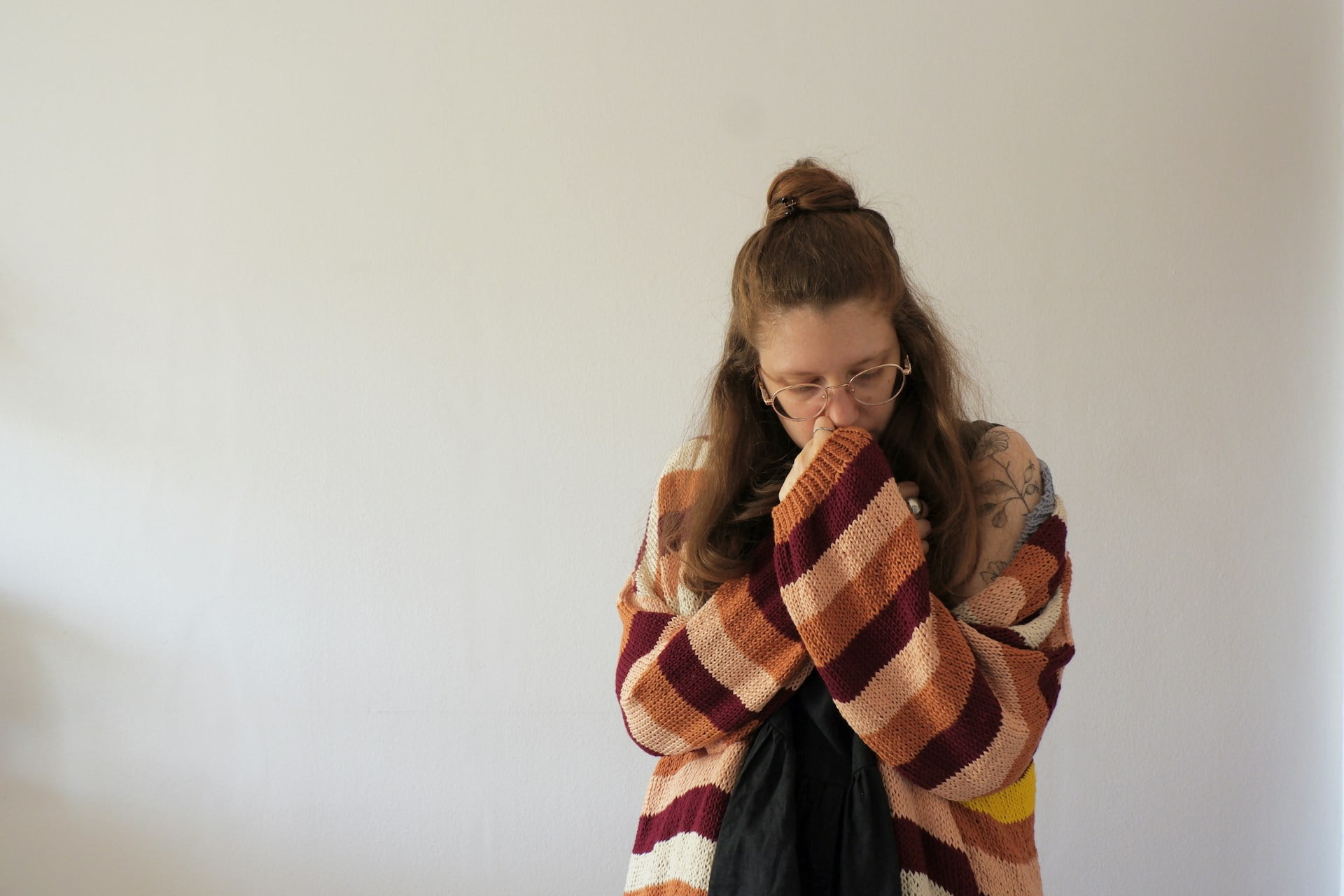 A woman suffering with trauma and addiction looking down, with her sleeve over her face